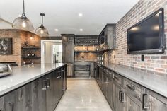 a large kitchen with brick walls and stainless steel appliances, along with an entertainment center