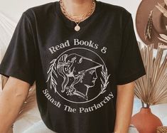 a woman wearing a black shirt with the words read books and smash the pattern on it