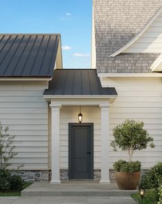 a white house with a gray door and black roof