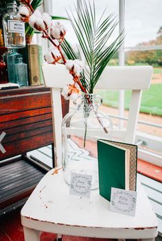 a white chair sitting next to a table with a vase filled with flowers on top of it