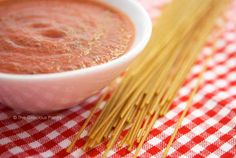 a small bowl of red sauce on top of a checkered table cloth