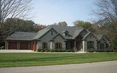 a large house with lots of windows in the front yard and trees on both sides