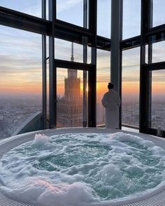 a man standing in front of a large window next to a hot tub filled with water