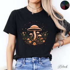 Mushroom Flowers and Stars Unisex Tee Shirt | Cottagecore Clothing | Botanical Boho Tshirt | Goblincore Aesthetic Clothes  ✔️ Soft, light and comfortable unisex short sleeve tee ✔️ 100% Airlume combed and ringspun cotton (fiber content may vary for different colours*) ✔️ Light fabric (4.2 oz/yd² (142 g/m ✔️ Retail fit 📏 Runs true to size ✔️ Dual side seams for structural support of the garment help hold its shape longer ✔️ Ribbed knit elastic collars to bolster shaping, twill taped shoulders to Black Graphic Tee With Mushroom Print, Fall Mushroom Design Crew Neck T-shirt, Fall Crew Neck T-shirt With Mushroom Design, Black Crew Neck T-shirt With Mushroom Print, Black Crew Neck Top With Mushroom Print, Black Short Sleeve Top With Mushroom Print, Fall Mushroom Print Graphic T-shirt, Fall Graphic Tee With Mushroom Print, Fall Mushroom Print Graphic Tee