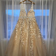 a dress hanging up on a hanger in front of a window with sheer curtains