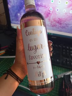 a person holding a bottle of wine in front of a computer