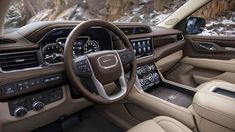 the interior of a vehicle with dashboard, steering wheel and center console in front of snowy mountains