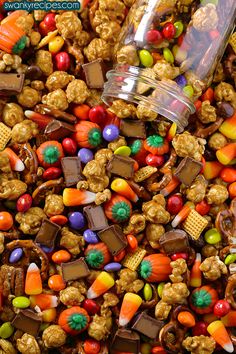 a pile of candy corn with a glass jar filled with it