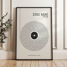 the song name poster is displayed in front of a wall with a potted plant