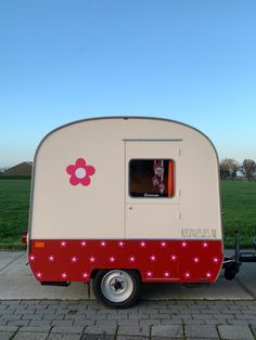 a red and white trailer parked on the side of a road next to a green field