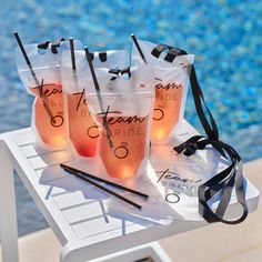 four bags filled with drinks sitting on top of a table next to a swimming pool