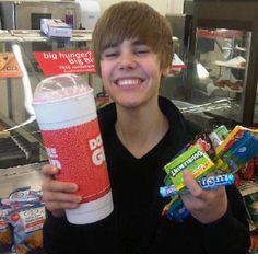 a boy holding up a cup and some candy