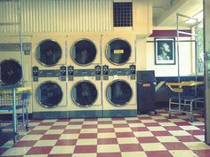 a row of washers sitting in a room with checkered flooring on the floor