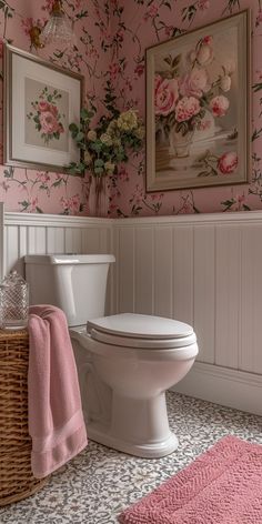 a white toilet sitting in a bathroom next to a pink rug and framed flowers on the wall