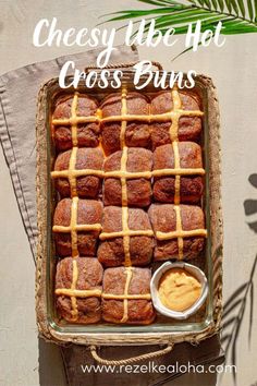 a pan filled with cross buns next to a bowl of peanut butter and a palm leaf