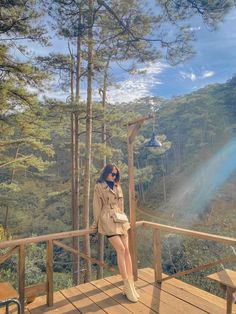 a woman sitting on top of a wooden deck next to a lush green forest under a blue sky