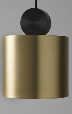 a black and gold lamp hanging from a ceiling fixture with a round light shade on it