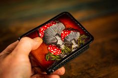 Handmade Leather Bifold Wallet - Vegetable-Tanned Leather, Tooled Amanita Muscaria Mushroom Design. Perfect for Foragers, Nature-Lovers, and Cottagecore Enthusiasts. Looking for a unique and handmade leather wallet that expresses your love for nature and the outdoors? Look no further than our Handmade Leather Bifold Wallet, featuring a whimsical Amanita Muscaria mushroom design tooled into the vegetable-tanned leather. This wallet is perfect for foragers, nature-lovers, and those with a taste fo Vegetable-tanned Leather Wallets For Gift, Vegetable-tanned Leather Wallet Gift, Handmade Leather Artisan Wallets, Custom Handmade Leather Trifold Wallet, Handmade Artisan Leather Trifold Wallet, Artisan Handmade Leather Trifold Wallet, Handmade Bifold Coin Purse, Handmade Leather Wallet For Daily Use, Handmade Leather Wallets For Daily Use