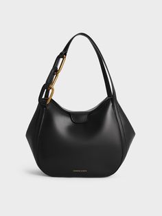 With the roomy interior of a classic tote, this black Kora bag is essentially two bags in one. Featuring a fold-over closure, which is secured with a magnetic clasp, this chic carrier comes with side flaps that can be tucked in or let out, so you can change it silhouette, as well as its carrying capacity, in an instant. In other words, this piece can be transformed to suit your needs and preferences. A bold and eye-catching chain-link detail on the handle makes it stand out even more. Charles And Keith, Top Handle Handbags, Charles Keith, Magnetic Clasp, Black Bag, Metallic Accents, Black Tote Bag, Sales Gifts, Trending Shoes