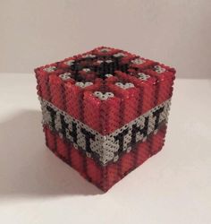 a red, black and white cube made out of legos on a white surface