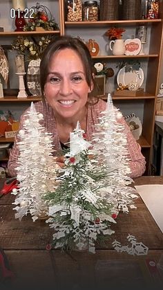 a woman sitting at a table with a fake christmas tree