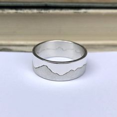 Mens personalised mountain ring handmade in silver.  Your own favourite mountain range features on this ring, creating the cut line between land and sky. Combining luxe elegance and contemporary design, this handmade silver ring captures the quiet beauty of the great outdoors. Made in two interlocking pieces, this bespoke silver ring can be cut to reflect a skyline or mountain range that holds significance to you. Hannah can work from your own photo of your favourite panorama if you have one. Th Mountain Ring, Surf Jewelry, Map Jewelry, Mountain Jewelry, Quiet Beauty, Handmade Silver Ring, Small Earrings Studs, Black Jewelry, Silver Rings Handmade