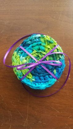 there is a crochet basket with purple ribbon on the table