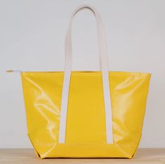 a yellow and white tote bag sitting on top of a wooden table next to a wall