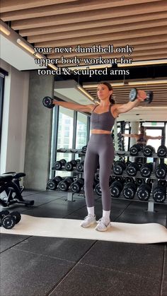 a woman is doing exercises in the gym with dumbbells on her chest and arms