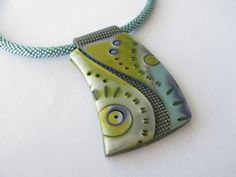 a green and blue necklace on a white surface