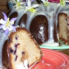 a bundt cake with white icing and blueberries on top sits next to a red plate