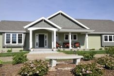 a house with a bench in front of it and bushes around the yard area on either side