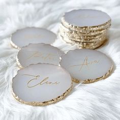 four white and gold coasters with writing on them