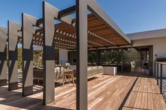 an outdoor living area with wooden flooring and pergolated roof