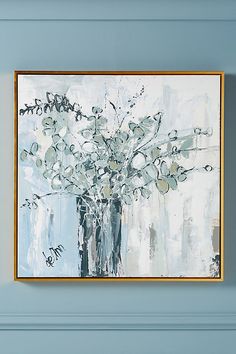 a painting hanging on the wall above a vase filled with flowers