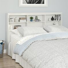 a bed with white headboard and pillows on top of it, next to a book shelf