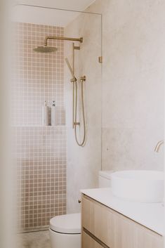 a white toilet sitting next to a sink in a bathroom under a faucet