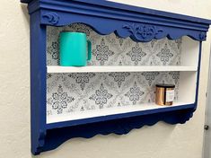 a blue shelf with two cups on it and a candle holder in front of it