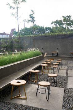 an outdoor seating area with wooden stools and plants on the roof terrace, surrounded by gravel