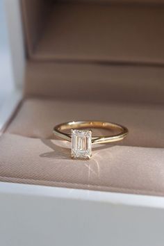 an engagement ring with a baguette cut diamond in it's box on display