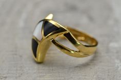 The Mintaka Contemporary 14K Mother of Pearl and Onyx Cocktail Ring. This crescent moon shaped ring is crafted in 14 karat yellow gold and features a mother of pearl section framed by black onyx sections to the north and south. The ring is currently a finger size 6.5 and is able to be resized. Each piece has been hand selected and meticulously identified and graded by a Graduate Gemologist who has been awarded a degree by the Gemological Institute of America (GIA). Please visit our Shop's About Elegant White Crescent Rings, Gold Enamel Ring With Inlay, Elegant Enamel Ring With Inlay, Elegant Gold Rings With Inlay, Gold Mother Of Pearl Ring For Gift, Classic Mother Of Pearl Rings, Elegant Black Rings With Inlay, Elegant White Mother Of Pearl Ring, Luxury Gold Mother Of Pearl Rings