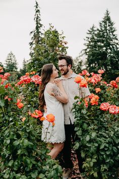 a man and woman standing next to each other in a field of flowers