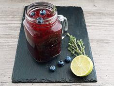 a glass jar filled with blueberries and lemon on top of a black slate board