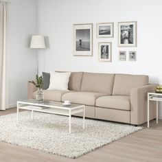 a living room with white furniture and pictures on the wall