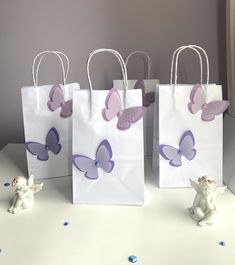 three bags with purple butterflies on them sitting on a table next to small figurines