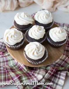 cupcakes with white frosting on a wooden plate