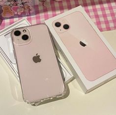 two pink iphones sitting next to each other on top of a table in front of a box