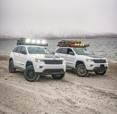 two white jeeps parked next to each other on a beach