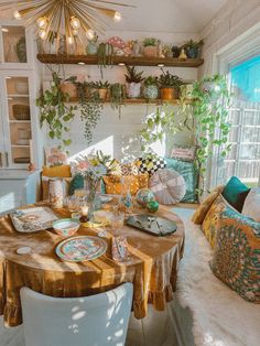 a dining room table with plates and place settings on it, surrounded by potted plants