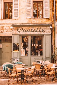 an outdoor cafe with tables and chairs in front of the storefront, surrounded by old buildings